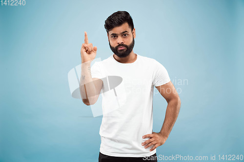 Image of Half-length close up portrait of young man on blue background.