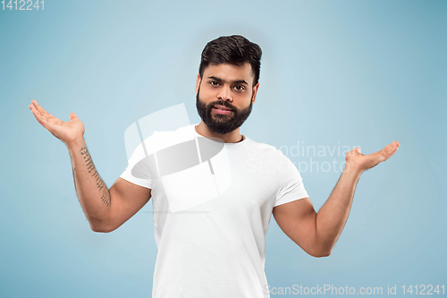 Image of Half-length close up portrait of young man on blue background.