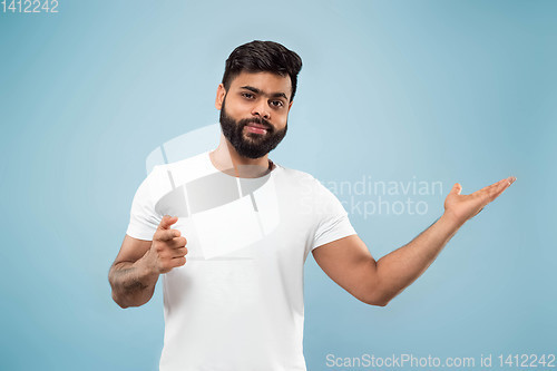 Image of Half-length close up portrait of young man on blue background.