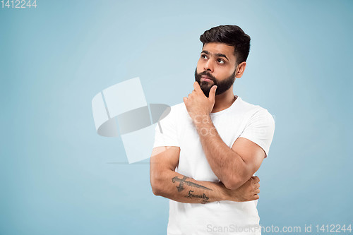 Image of Half-length close up portrait of young man on blue background.
