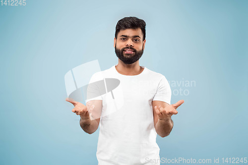 Image of Half-length close up portrait of young man on blue background.