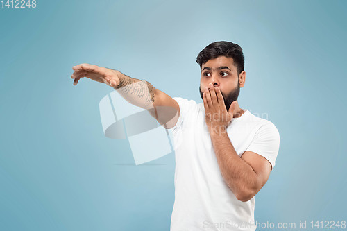 Image of Half-length close up portrait of young man on blue background.