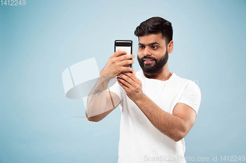 Image of Half-length close up portrait of young man on blue background.