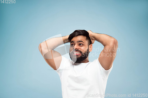 Image of Half-length close up portrait of young man on blue background.