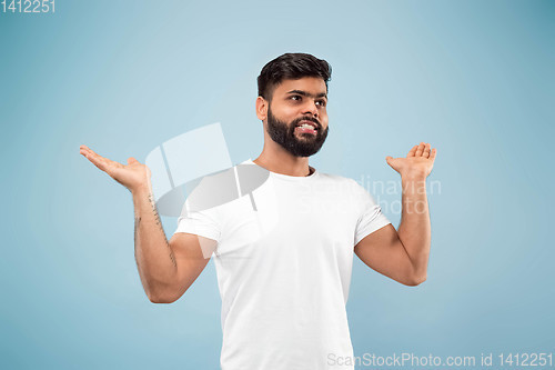 Image of Half-length close up portrait of young man on blue background.