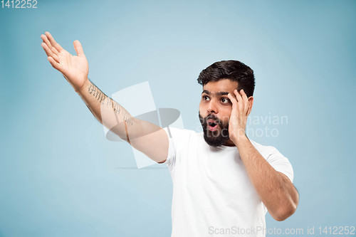Image of Half-length close up portrait of young man on blue background.