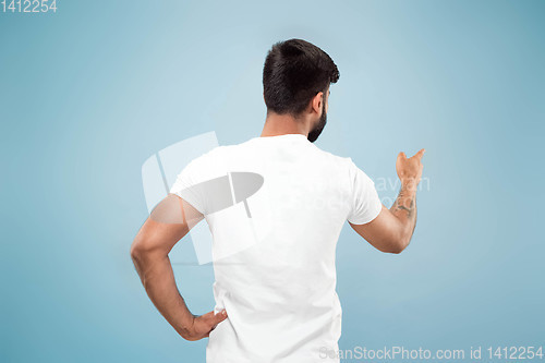 Image of Half-length close up portrait of young man on blue background.