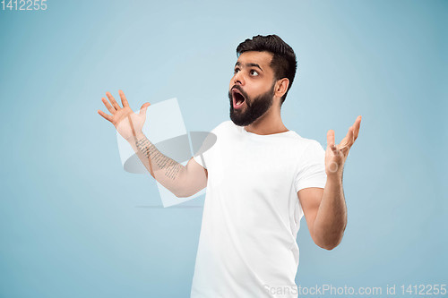 Image of Half-length close up portrait of young man on blue background.