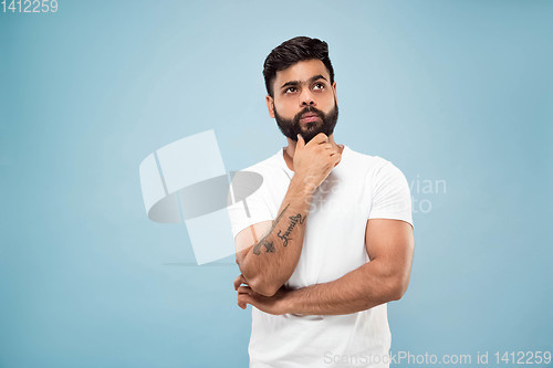 Image of Half-length close up portrait of young man on blue background.