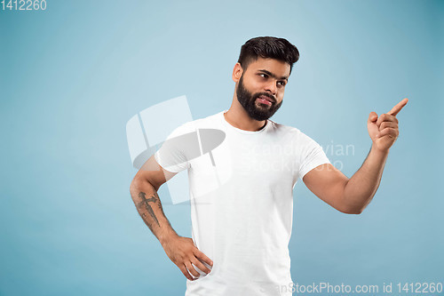 Image of Half-length close up portrait of young man on blue background.