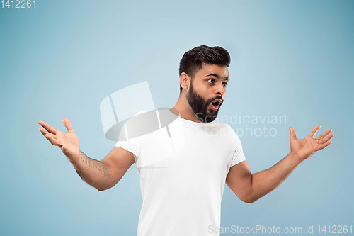 Image of Half-length close up portrait of young man on blue background.