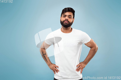 Image of Half-length close up portrait of young man on blue background.