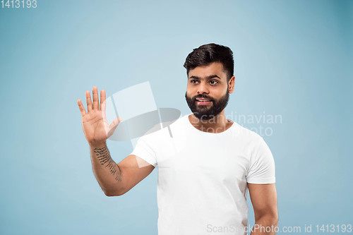 Image of Half-length close up portrait of young man on blue background.