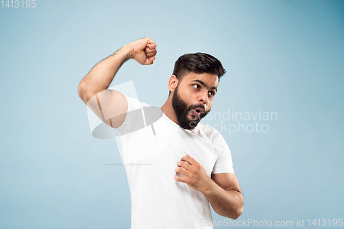 Image of Half-length close up portrait of young man on blue background.