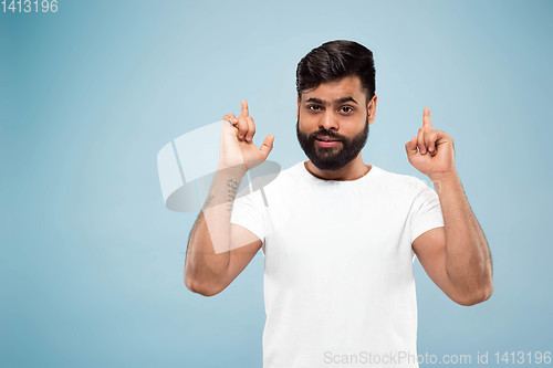 Image of Half-length close up portrait of young man on blue background.