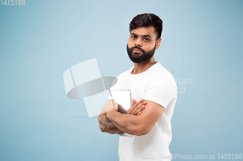 Image of Half-length close up portrait of young man on blue background.