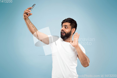 Image of Half-length close up portrait of young man on blue background.