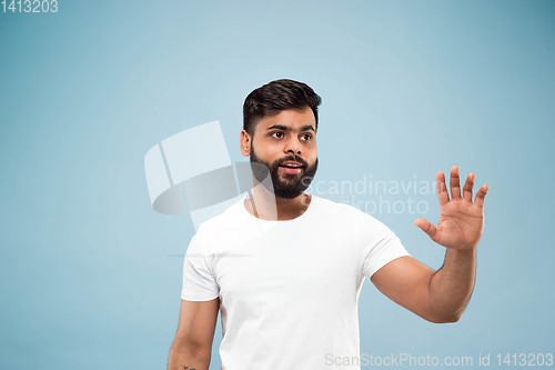 Image of Half-length close up portrait of young man on blue background.