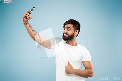 Image of Half-length close up portrait of young man on blue background.