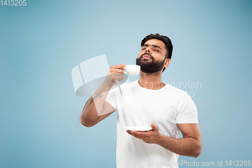 Image of Half-length close up portrait of young man on blue background.