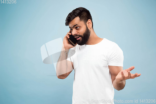 Image of Half-length close up portrait of young man on blue background.