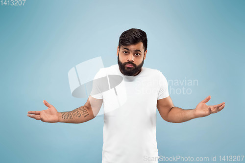 Image of Half-length close up portrait of young man on blue background.