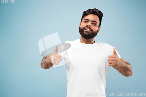 Image of Half-length close up portrait of young man on blue background.