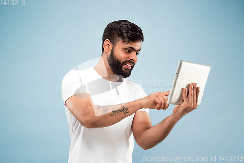 Image of Half-length close up portrait of young man on blue background.