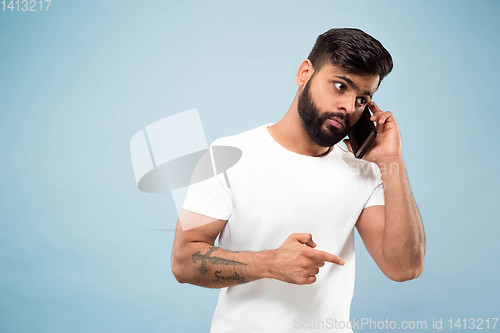 Image of Half-length close up portrait of young man on blue background.