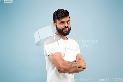 Image of Half-length close up portrait of young man on blue background.