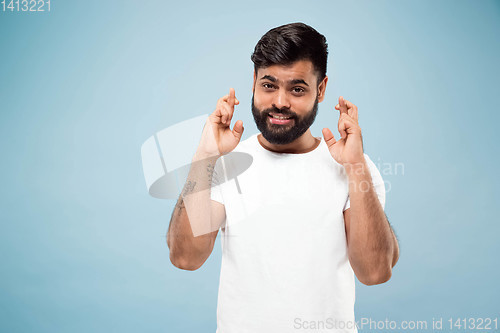 Image of Half-length close up portrait of young man on blue background.