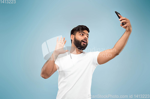 Image of Half-length close up portrait of young man on blue background.