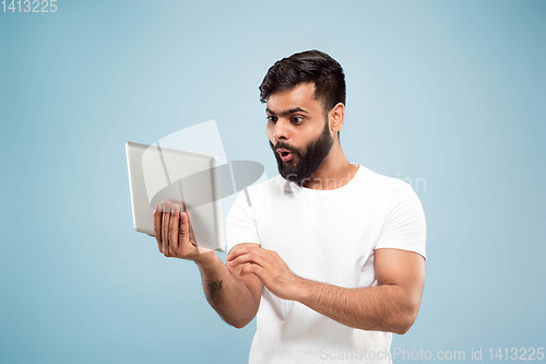 Image of Half-length close up portrait of young man on blue background.