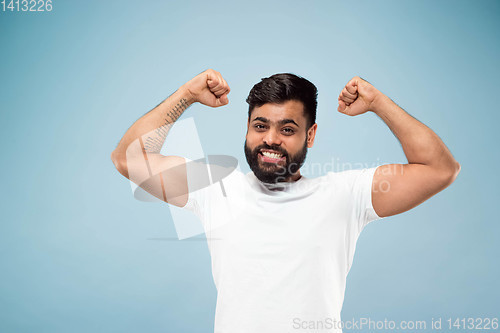 Image of Half-length close up portrait of young man on blue background.