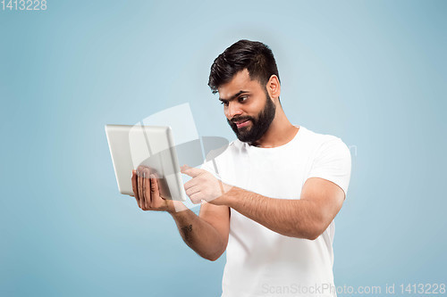 Image of Half-length close up portrait of young man on blue background.