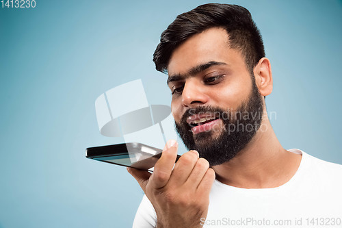 Image of Half-length close up portrait of young man on blue background.