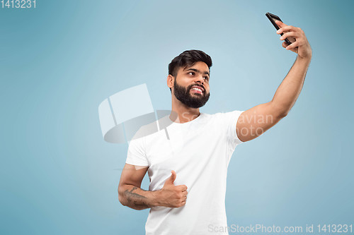 Image of Half-length close up portrait of young man on blue background.