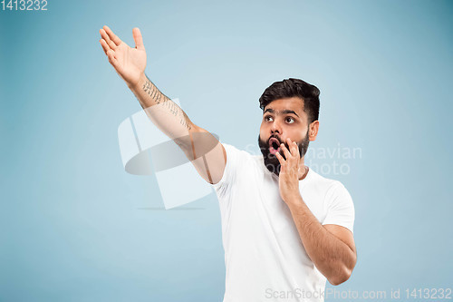 Image of Half-length close up portrait of young man on blue background.
