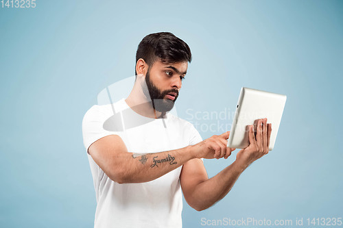 Image of Half-length close up portrait of young man on blue background.