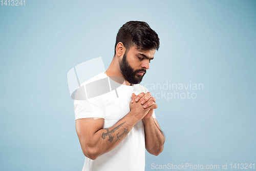 Image of Half-length close up portrait of young man on blue background.