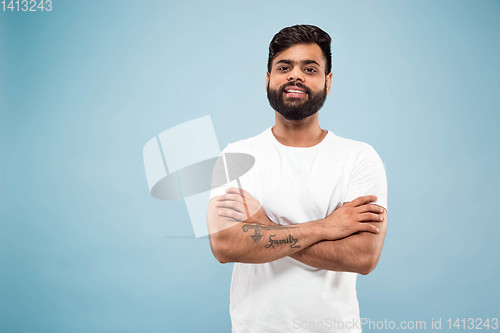 Image of Half-length close up portrait of young man on blue background.
