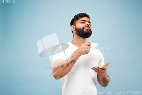 Image of Half-length close up portrait of young man on blue background.