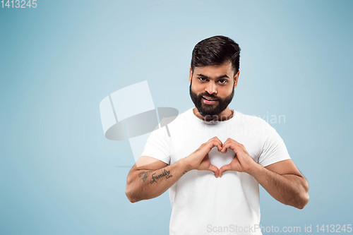Image of Half-length close up portrait of young man on blue background.