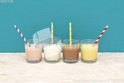 Image of Flavoured milkshakes and milk with straws in glass tumblers