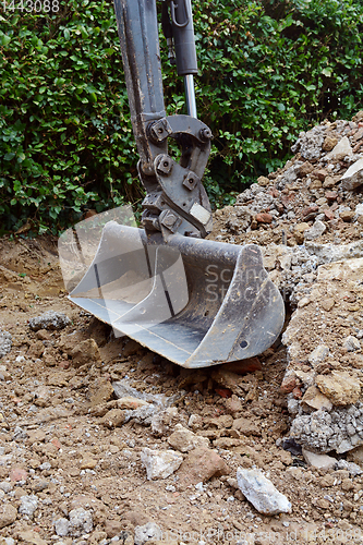 Image of Metal digger bucket resting on broken concrete and bricks