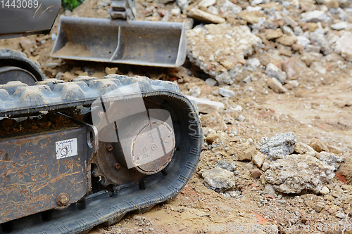 Image of Rubber track of a digger against concrete and earth debris