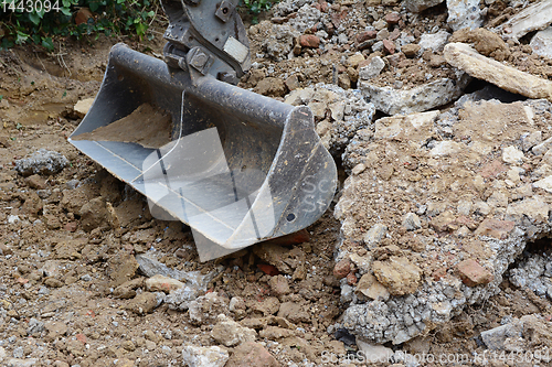 Image of Heavy duty metal digger bucket among piles of rough rubble