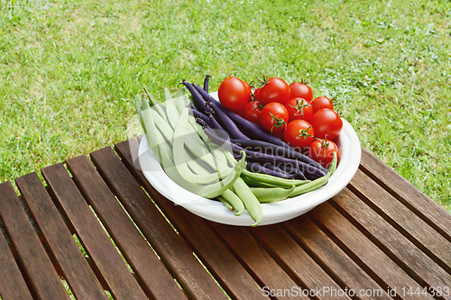 Image of Freshly harvested beans and cherry tomatoes on a wooden table 