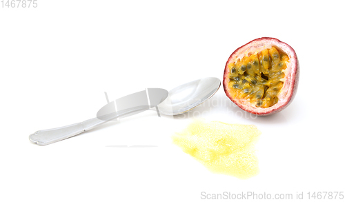 Image of Half passion fruit showing yellow pulp and seeds with spoon