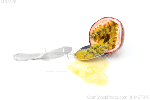 Image of Spoon scooping out seeds from half a purple passion fruit